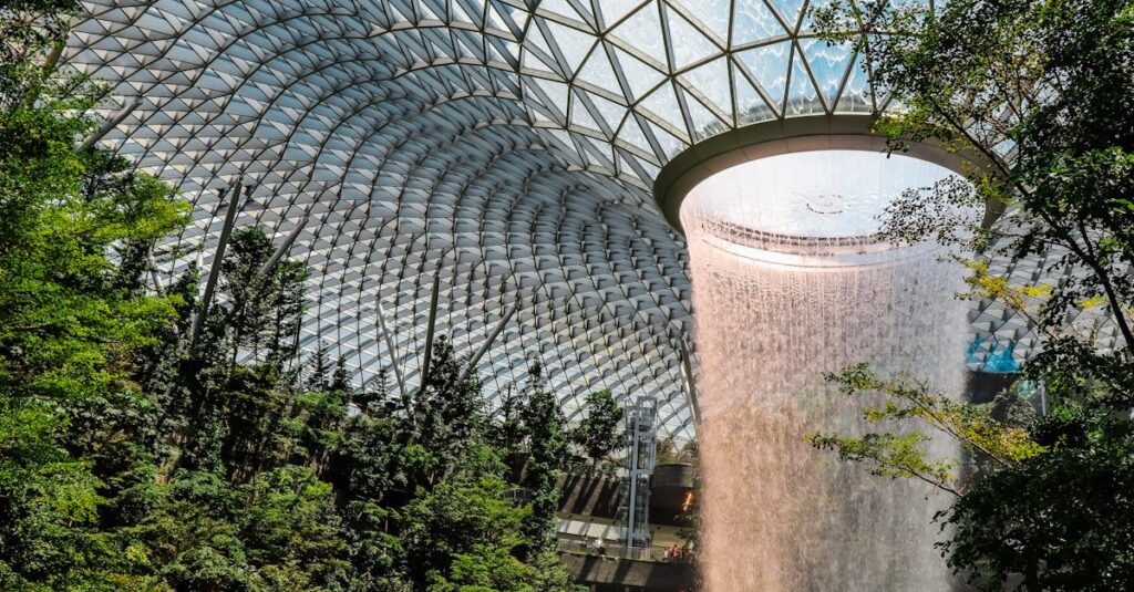 The iconic indoor waterfall at Jewel Changi Airport surrounded by lush gardens.